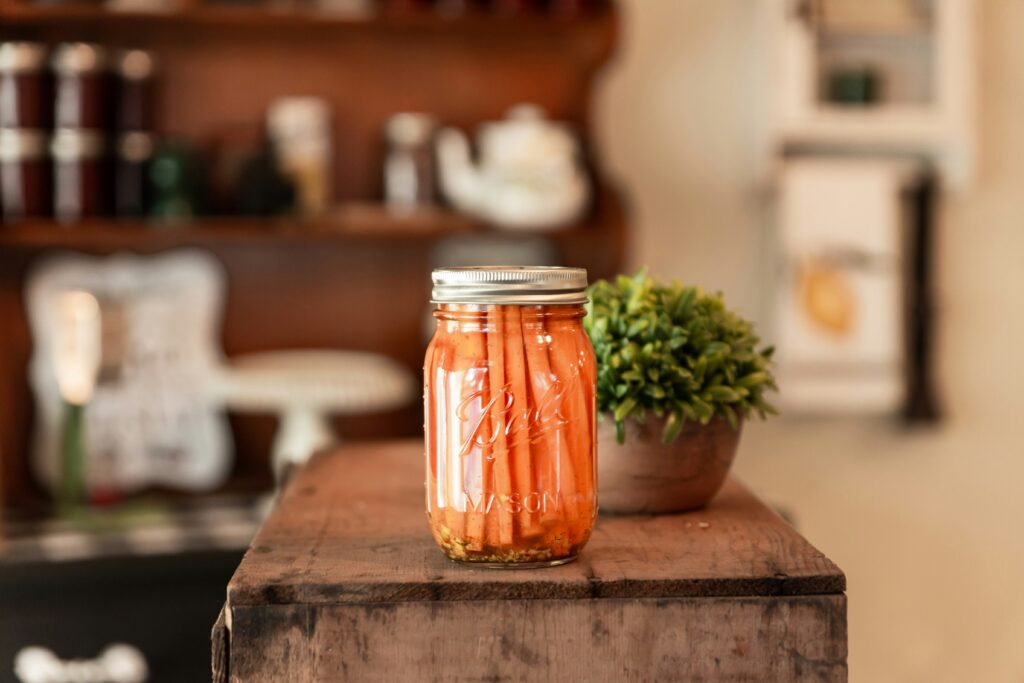 homesteading skills for beginners – pickled carrots in a Ball mason jar on a wooden surface